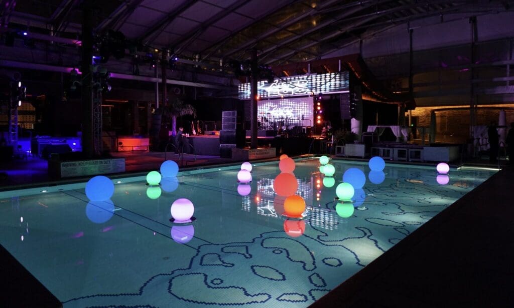 Lighted orbs float in a pool at night.